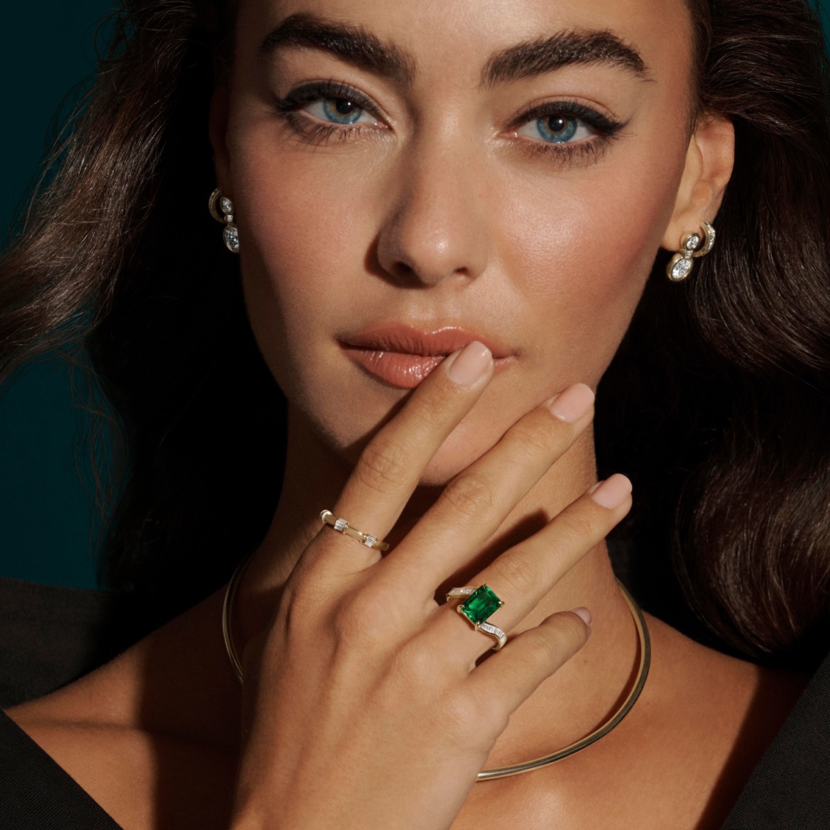 Model wearing an emerald ring and diamond earrings from the Elizabeth Taylor Collection